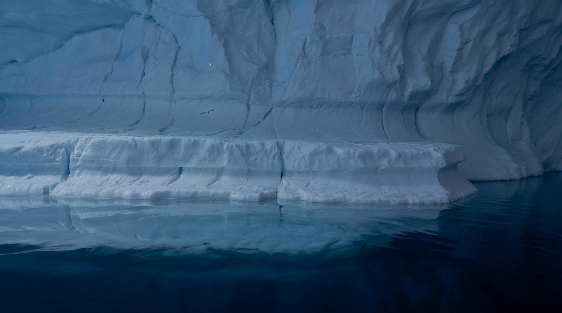 A stepped ice shelf inside the iceberg descending into the water in two separate levels.